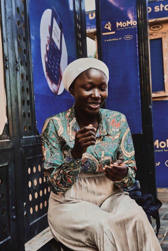 Portrait of a smiling woman seated outdoors, engaging with her surroundings.